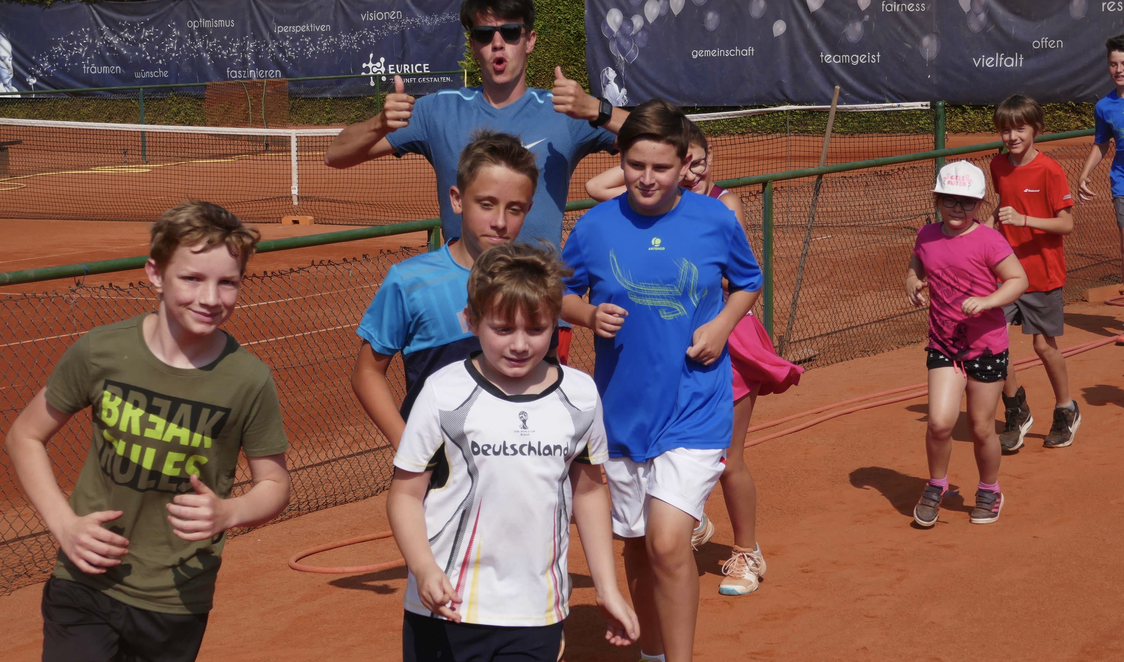 Bild vom Tenniscamp 2020. Zu sehen sind Kinder die sich gemeinsam mit dem Trainer warmlaufen.